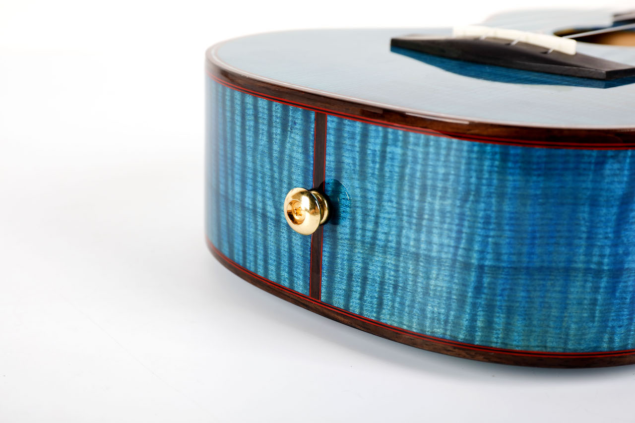 Gold strap button at base of Enya Flower ukulele